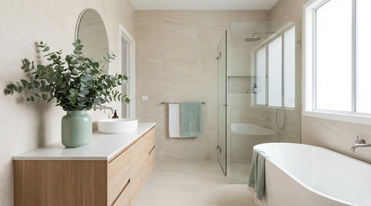 A clean bright modern Australian bathroom, natural light from a window, pale stone tiles, timber vanity, eucalyptus in a