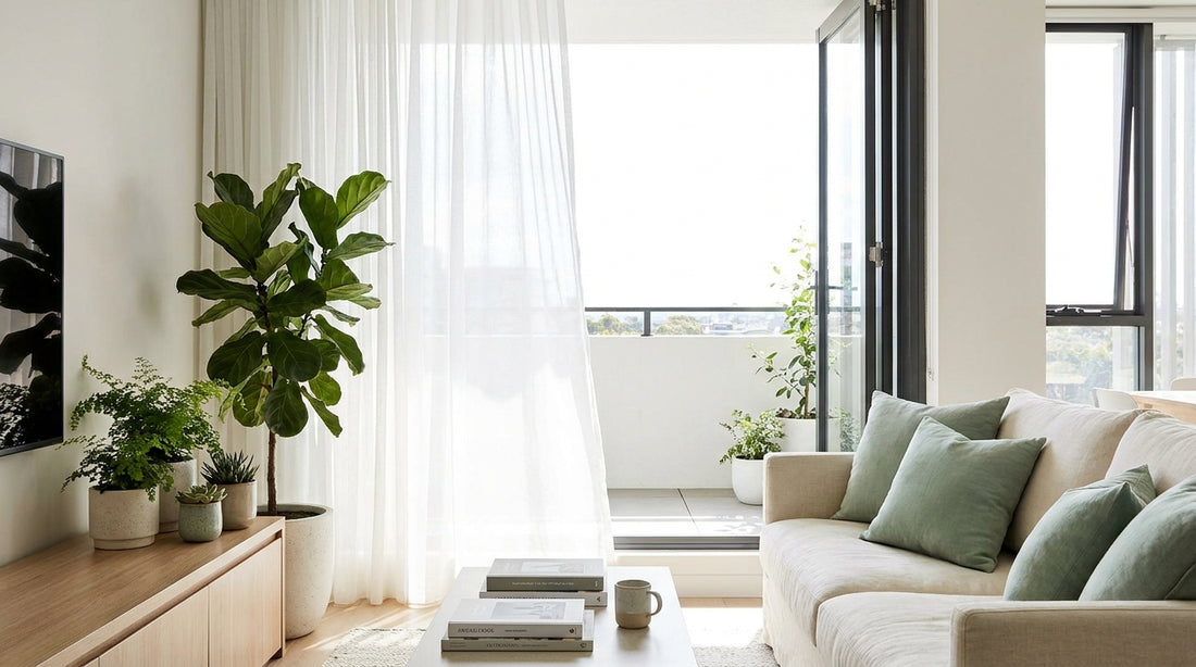 A bright airy contemporary Australian apartment living space, open window, sheer curtains, indoor plants, sage-mint acce